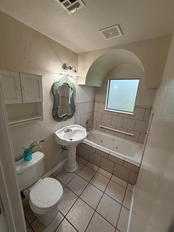 6300 S Hiwassee Rd, Oklahoma City, OK 73150 - full bathroom featuring a textured wall, a tub with jets, tile patterned flooring, and toilet