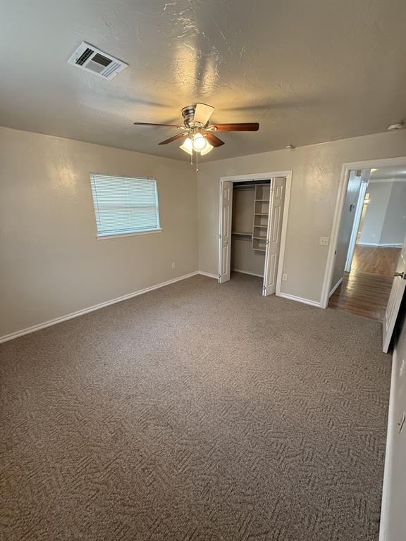 6300 S Hiwassee Rd, Oklahoma City, OK 73150 - unfurnished bedroom featuring baseboards, carpet floors, a closet, ceiling fan, and a textured ceiling