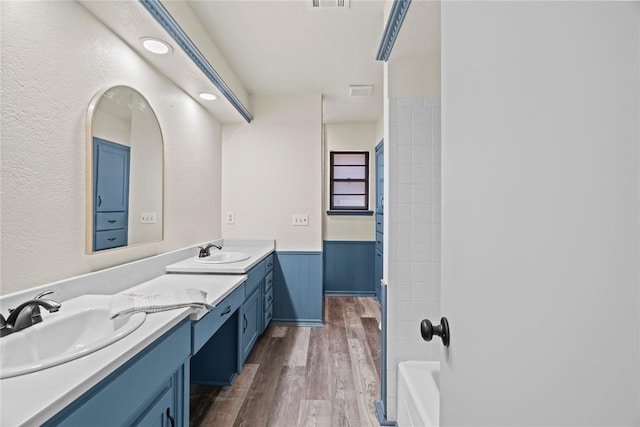 9800 Honeysuckle Rd, Oklahoma City, OK 73159 - bathroom with a wainscoted wall, double vanity, a sink, and wood finished floors