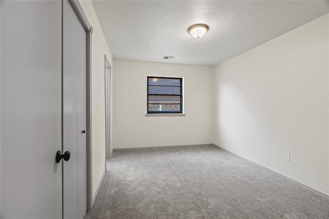 9800 Honeysuckle Rd, Oklahoma City, OK 73159 - unfurnished bedroom featuring a closet, a textured ceiling, visible vents, and carpet floors