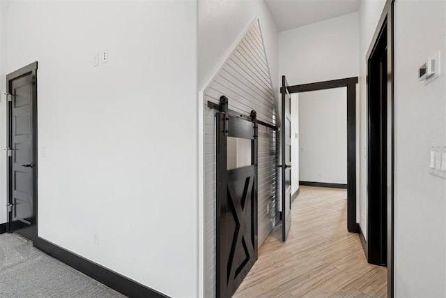 7217 Painted Sky Dr, Edmond, OK 73034 - hallway with a barn door, baseboards, and light wood finished floors