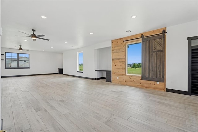 7217 Painted Sky Dr, Edmond, OK 73034 - unfurnished living room with a barn door, plenty of natural light, light wood finished floors, recessed lighting, and baseboards
