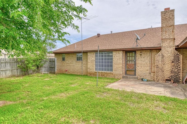 rear view of property featuring a yard, a chimney, fence, a patio area, and roof with shingles