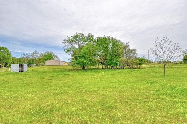view of yard with fence, a rural view, and an outbuilding