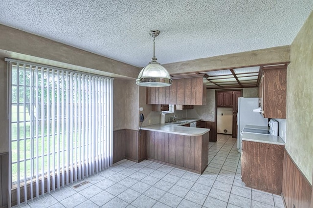 kitchen with a peninsula, a sink, a textured ceiling, visible vents, and light countertops