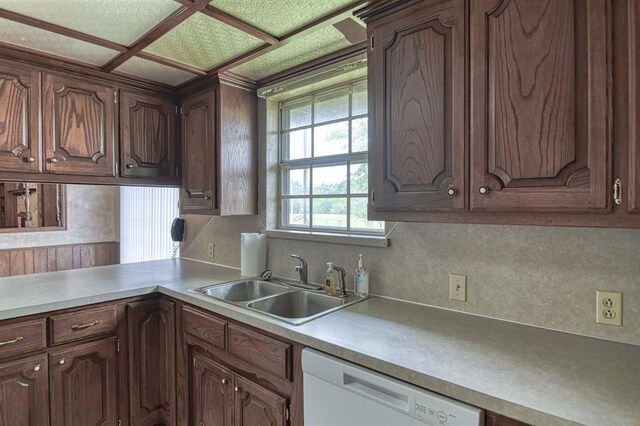 kitchen with backsplash, light countertops, a sink, and white dishwasher