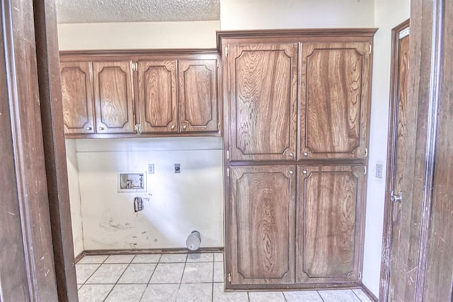 laundry room with cabinet space, a textured ceiling, light tile patterned floors, electric dryer hookup, and hookup for a washing machine