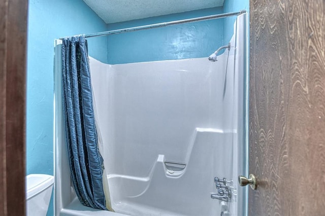 bathroom featuring toilet, shower / tub combo with curtain, and a textured ceiling