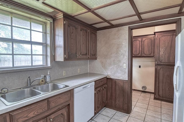 kitchen featuring a sink, white appliances, light countertops, and a wealth of natural light