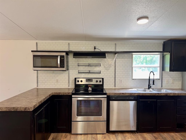 559 Poppy Rd, Broken Bow, OK 74728 - kitchen with light wood-style flooring, a sink, dark countertops, tasteful backsplash, and appliances with stainless steel finishes