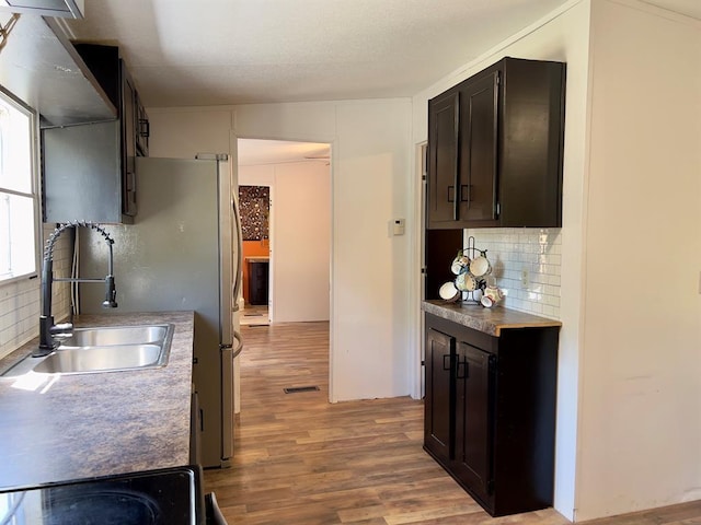 559 Poppy Rd, Broken Bow, OK 74728 - kitchen featuring light wood-style flooring, a sink, dark brown cabinetry, visible vents, and tasteful backsplash