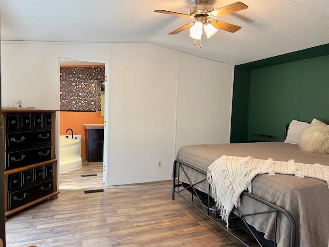 559 Poppy Rd, Broken Bow, OK 74728 - bedroom featuring wood finished floors, visible vents, vaulted ceiling, a ceiling fan, and connected bathroom