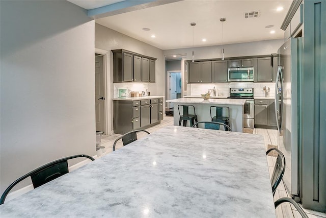 2107 NW 20th St, Oklahoma City, OK 73107 - kitchen with stainless steel appliances, backsplash, a kitchen breakfast bar, a center island, and light countertops