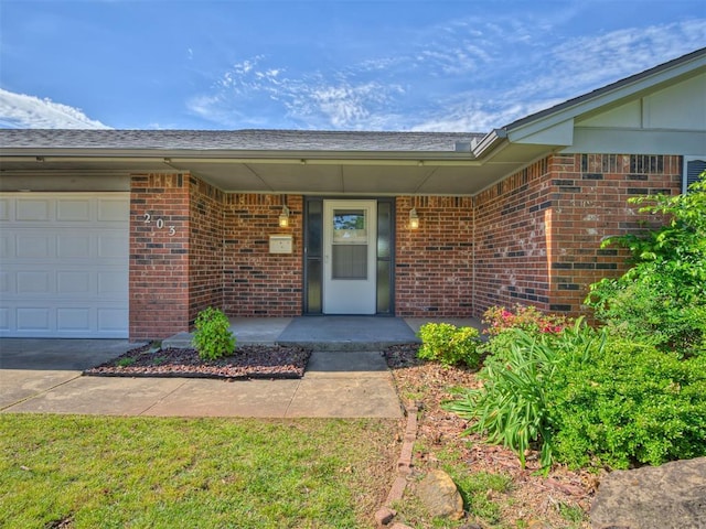 view of exterior entry featuring brick siding and a garage