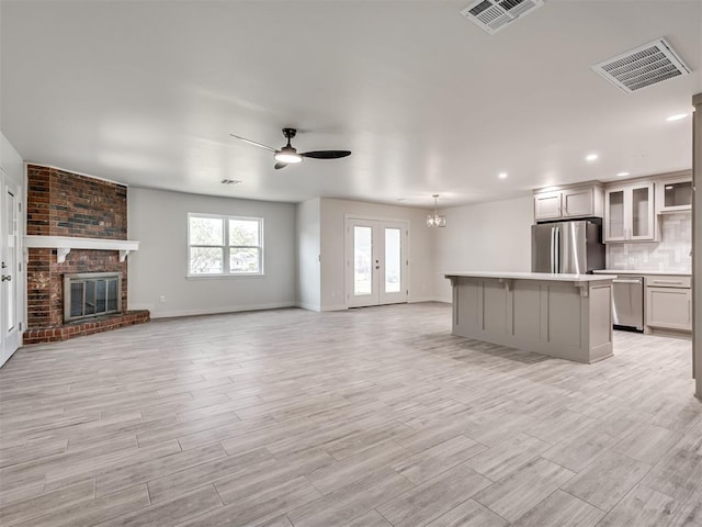 unfurnished living room featuring a ceiling fan, a brick fireplace, light wood-style floors, recessed lighting, and baseboards