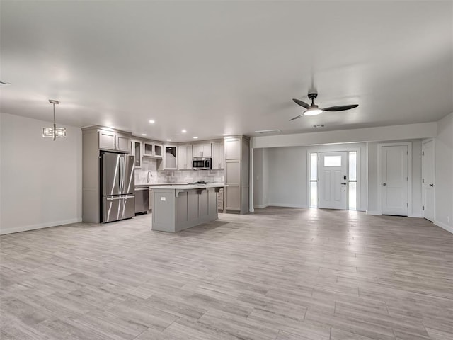 kitchen featuring stainless steel appliances, open floor plan, baseboards, a center island, and recessed lighting