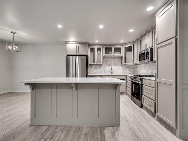 kitchen with stainless steel appliances, gray cabinetry, a center island, light countertops, and recessed lighting