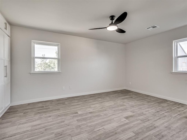 spare room with a ceiling fan, light wood-style floors, and baseboards