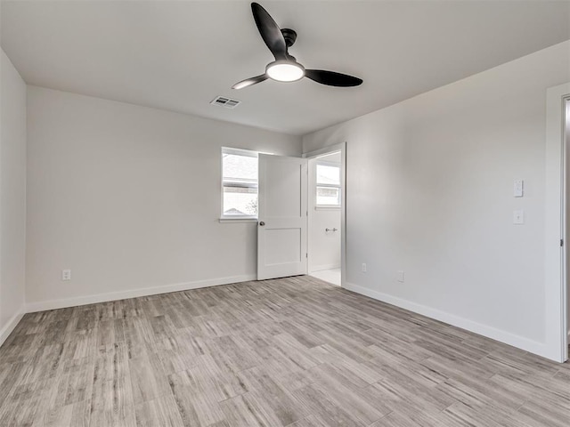 spare room with a ceiling fan, light wood finished floors, and baseboards
