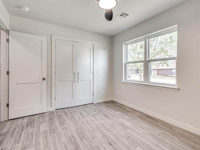 unfurnished bedroom featuring baseboards, light wood-style flooring, and a closet