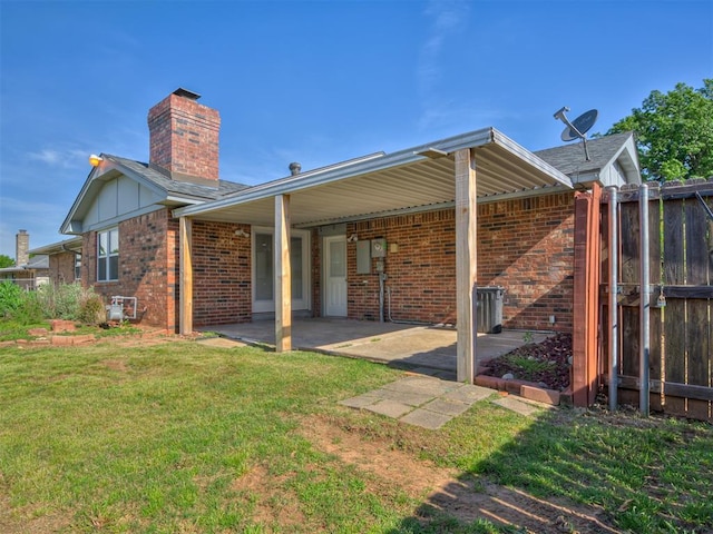 rear view of property with brick siding, a chimney, and a patio area