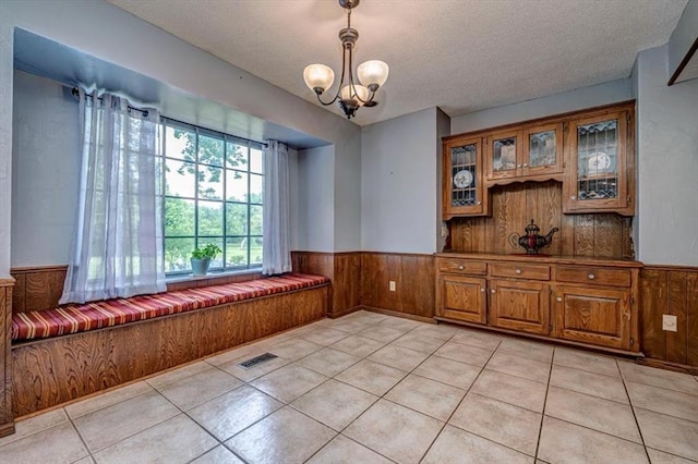 11125 NW 116th St, Yukon, OK 73099 - unfurnished dining area with wainscoting, a textured ceiling, wood walls, a chandelier, and light tile patterned flooring