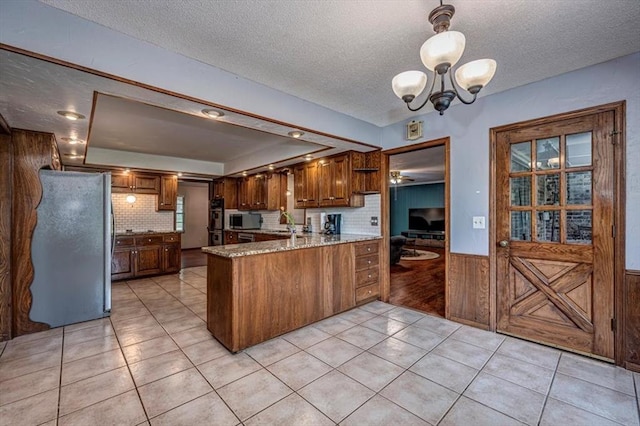 11125 NW 116th St, Yukon, OK 73099 - kitchen featuring stainless steel appliances, a peninsula, a textured ceiling, a raised ceiling, and a chandelier
