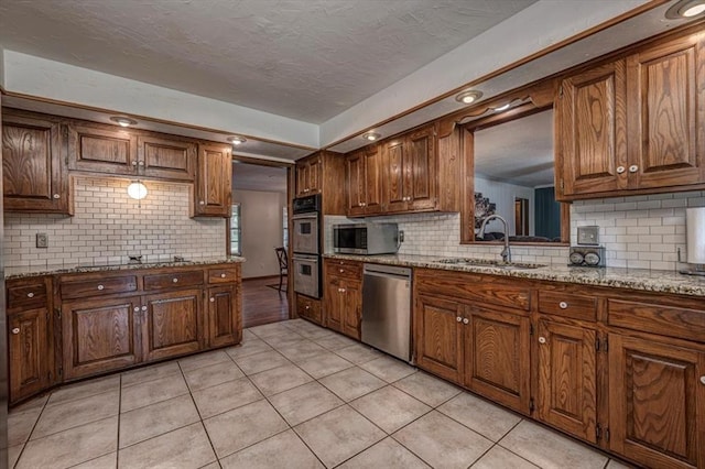 11125 NW 116th St, Yukon, OK 73099 - kitchen with stainless steel appliances, a sink, light tile patterned flooring, decorative backsplash, and a textured ceiling