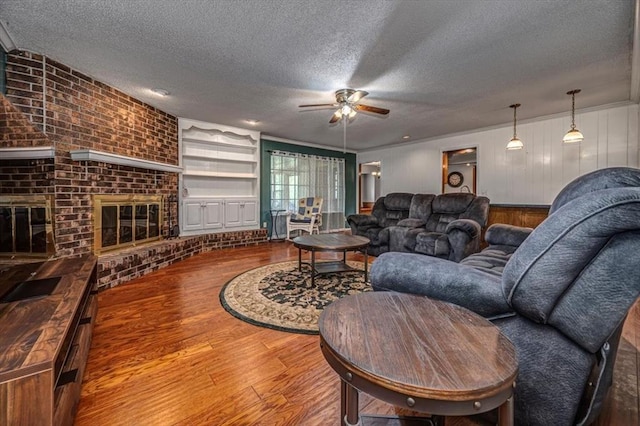 11125 NW 116th St, Yukon, OK 73099 - living room with ceiling fan, wood finished floors, a textured ceiling, and a fireplace