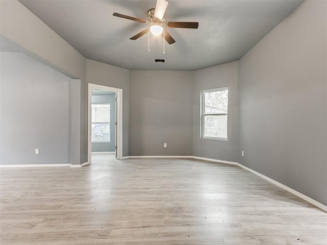 unfurnished room featuring a healthy amount of sunlight, light wood-style flooring, ceiling fan, and visible vents