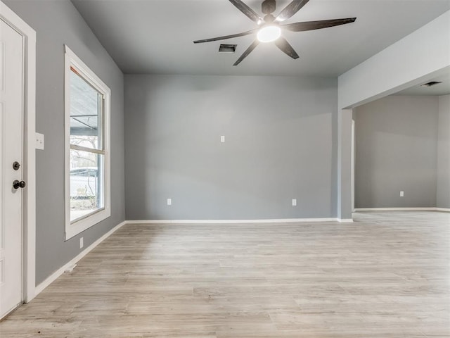 empty room with baseboards, ceiling fan, light wood finished floors, and visible vents