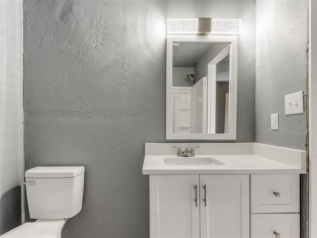 bathroom with toilet, vanity, and a textured wall