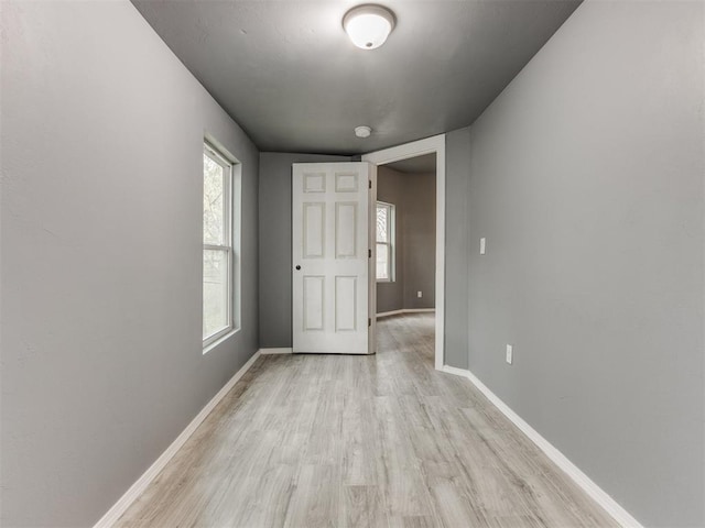 unfurnished room featuring baseboards and light wood-type flooring