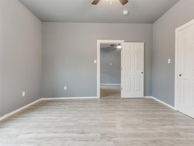 spare room featuring light wood-style floors, baseboards, and ceiling fan