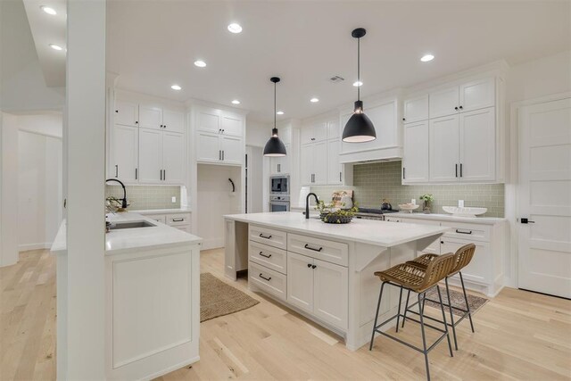 6516 NE 97th St, Oklahoma City, OK 73151 - kitchen with stainless steel appliances, tasteful backsplash, light countertops, light wood-style floors, and a kitchen breakfast bar