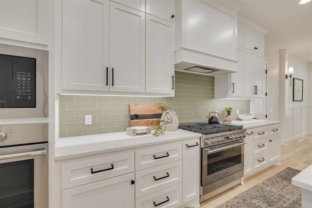 6516 NE 97th St, Oklahoma City, OK 73151 - kitchen featuring appliances with stainless steel finishes, custom exhaust hood, white cabinetry, light wood-style flooring, and tasteful backsplash