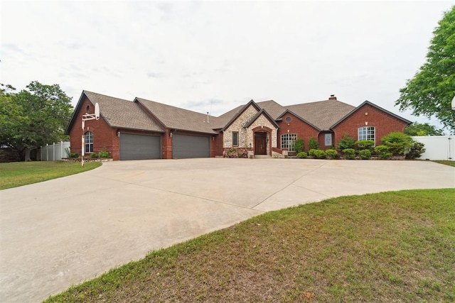 french country home with a garage, brick siding, concrete driveway, and a chimney