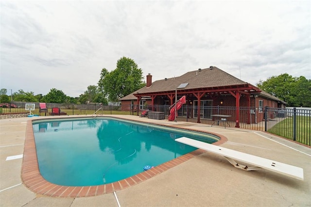 view of swimming pool featuring a diving board, fence, and a patio