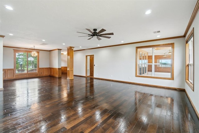 spare room featuring ornate columns, dark wood-style flooring, ornamental molding, a wainscoted wall, and recessed lighting