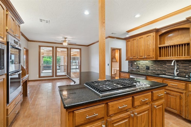 kitchen with stainless steel appliances, a sink, backsplash, light wood-style flooring, and crown molding