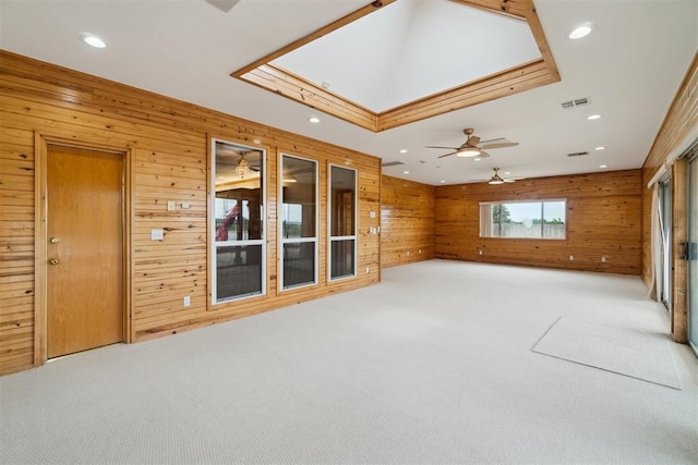 spare room featuring light carpet, wooden walls, recessed lighting, and ceiling fan