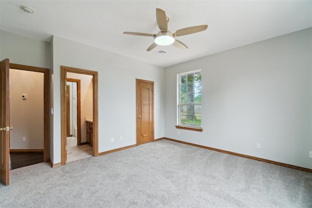 unfurnished bedroom featuring carpet floors, baseboards, connected bathroom, and ceiling fan