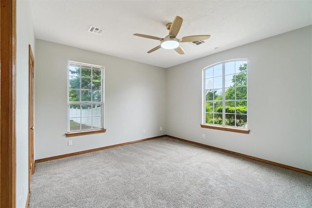 unfurnished room featuring plenty of natural light, carpet, ceiling fan, and baseboards