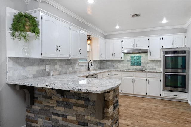 6408 Brentford Ter, Oklahoma City, OK 73132 - kitchen featuring stainless steel double oven, a peninsula, black electric stovetop, white cabinets, and ornamental molding
