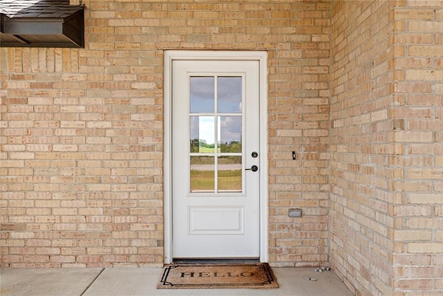 view of exterior entry featuring brick siding
