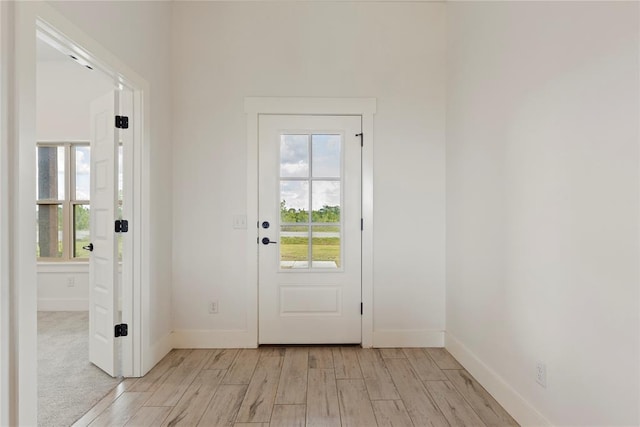 doorway to outside featuring light wood-style flooring, healthy amount of natural light, and baseboards