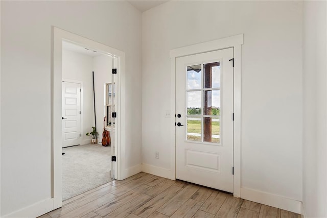 doorway to outside with light wood-type flooring and baseboards