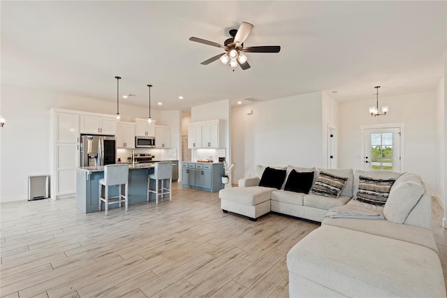 living area featuring a chandelier, light wood-style flooring, ceiling fan, and recessed lighting