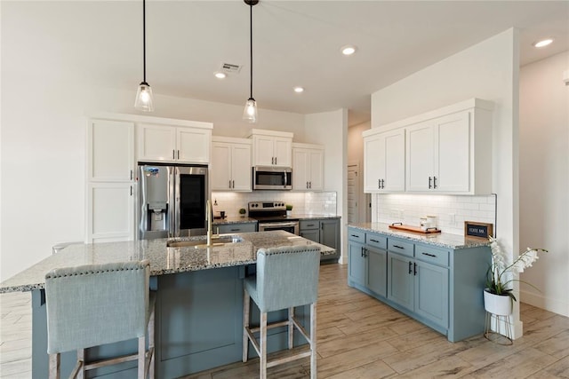 kitchen featuring stainless steel appliances, a sink, tasteful backsplash, a kitchen breakfast bar, and light wood-style flooring