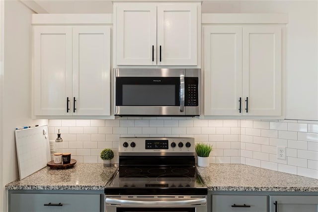 kitchen with stainless steel appliances, decorative backsplash, light stone countertops, and white cabinets